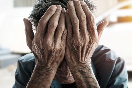 old man holding his head in his hands